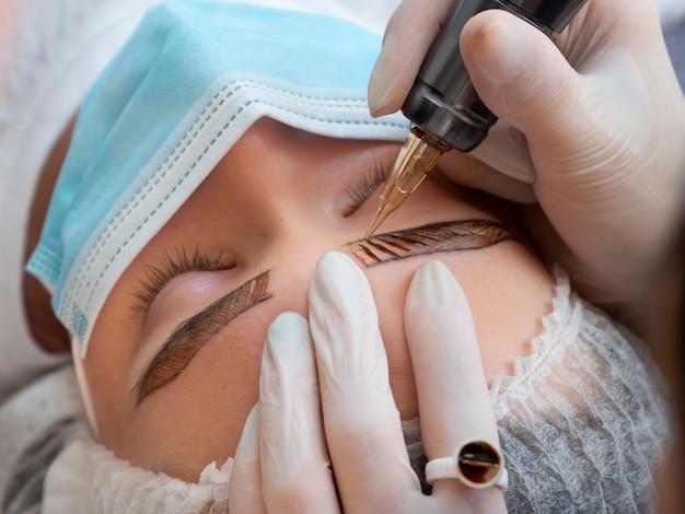 Dermatologist performing a skin treatment on a woman's forehead.