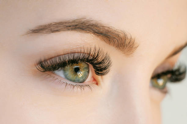 Close-up of a woman's face focusing on her green eyes with long eyelashes.